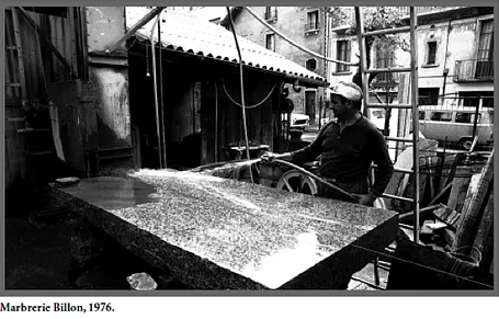 Photo d'archive en noir et blanc de 1976 montrant un marbrier travaillant une pierre dans un atelier