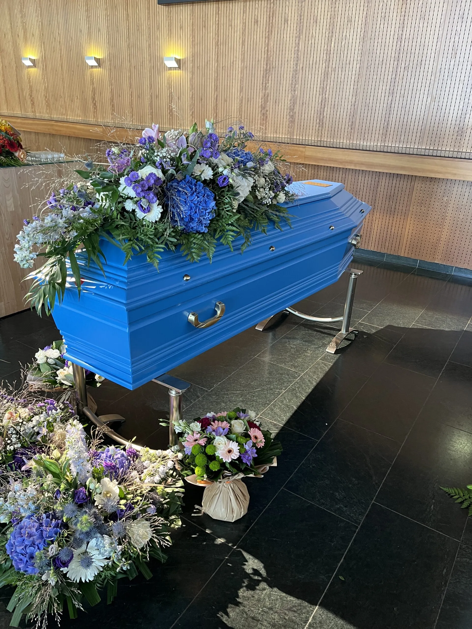 Cercueil en bois peint en bleu orné d'une composition florale de fleurs bleues et blanches